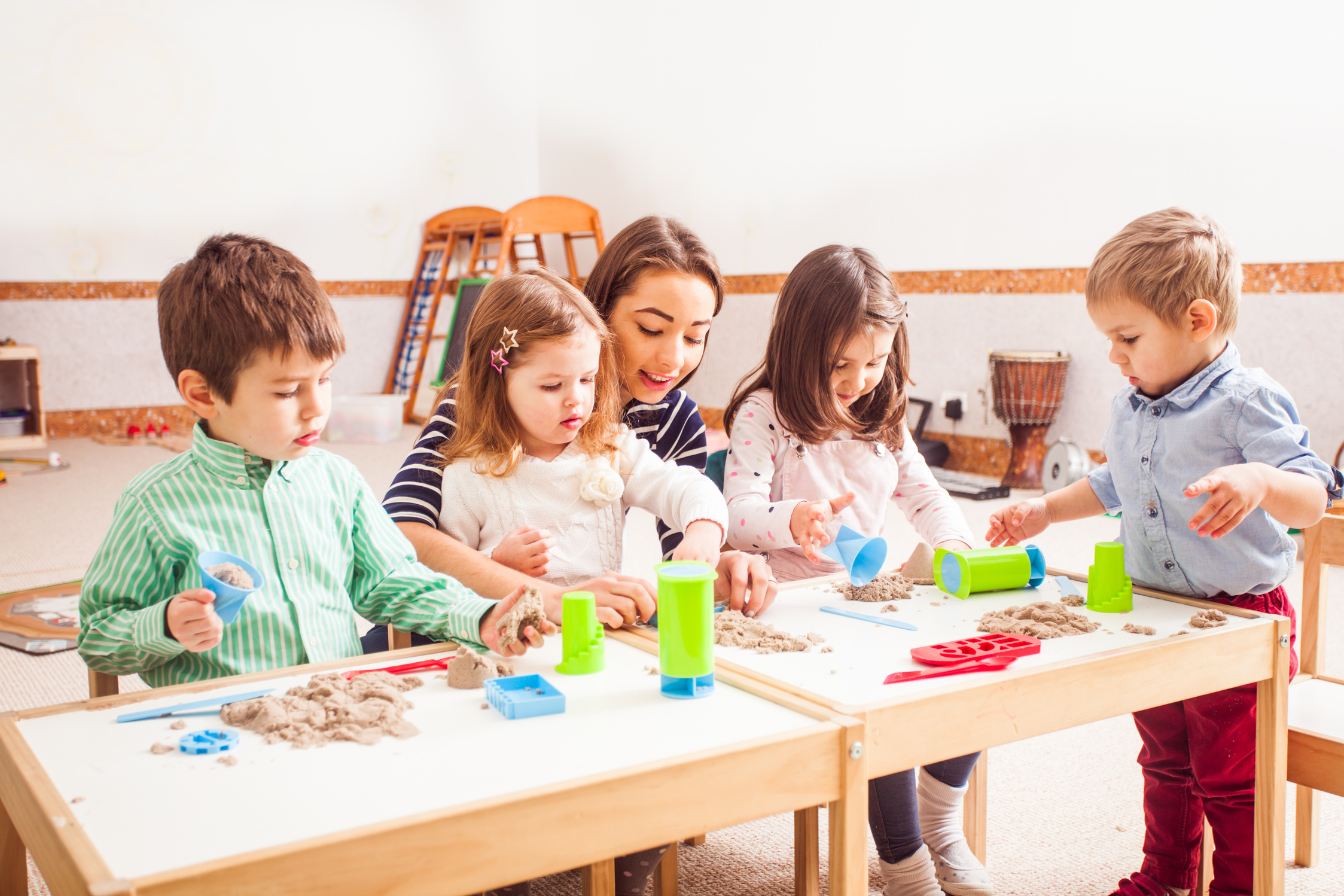 Group of Children and Babysitter Playing Kinetic Sand Indoors